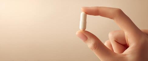 The hand holding a white capsule against a soft blurred background. photo