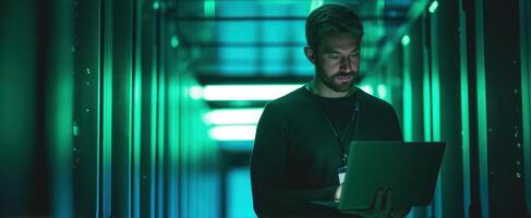 The focused man working on a laptop in a high-tech server environment. photo
