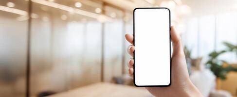 The modern smartphone held in hand against a blurred office background. photo