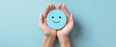 The Hands Holding a Smiling Blue Circle on a Light Background photo