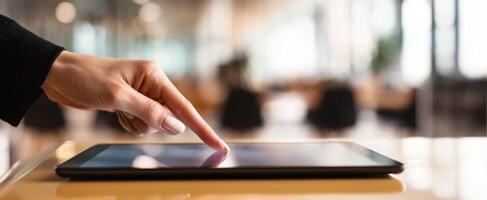 The hand interacting with a tablet screen in a modern office environment. photo