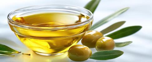 The bowl of olive oil with fresh olives and leaves on a light background. photo