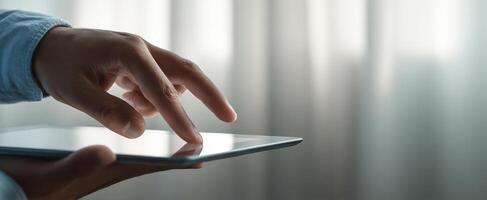 The hand interacting with a tablet against a softly lit background. photo