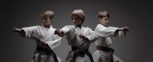 The three young karate practitioners demonstrating their skills and focus in the studio. photo