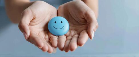 The hands holding a blue smiley face conveying joy and positivity. photo