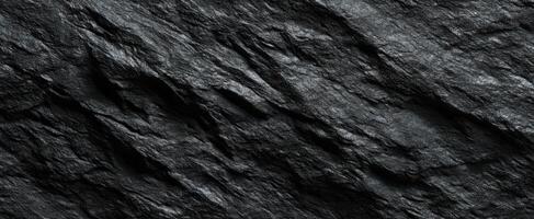 The textured black surface of natural stone with intricate patterns and shadows. photo