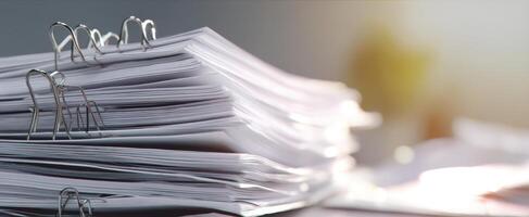 The stack of organized documents with binder clips on a workspace desk. photo