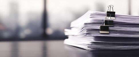 The stack of organized documents held together by binder clips. photo