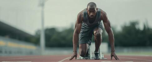 The focused athlete preparing to sprint on a running track. photo