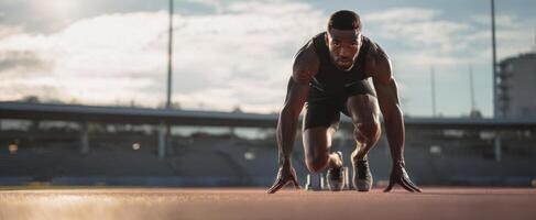 The athlete ready for a sprint on the track at sunset. photo