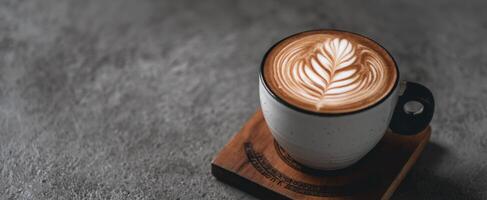 The beautiful latte art in a cozy coffee cup on a wooden coaster. photo