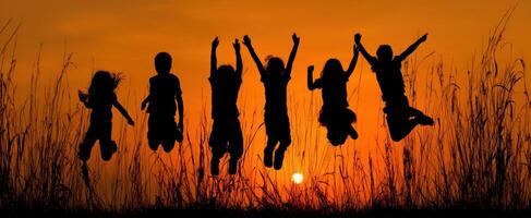 The joyous silhouette of children jumping against a vibrant sunset backdrop. photo