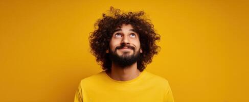 The man with curly hair smiling against a bright yellow background. photo