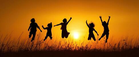 The joyful children jumping in silhouette against a vibrant sunset background. photo