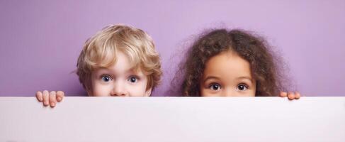 The adorable children peeking over a blank space with joyful expressions. photo