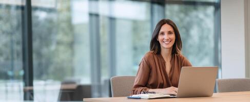 The smiling woman working at her laptop in a modern office setting. photo
