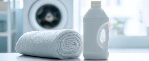 The detergent bottle beside a neatly rolled towel in a modern laundry room. photo