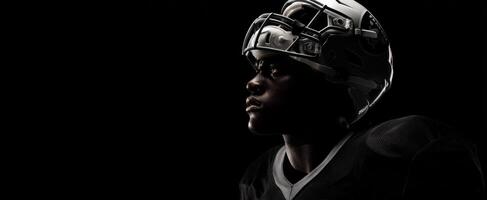 The determined football player in a dramatic profile against a dark background. photo