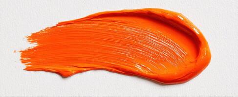 The vibrant orange paint stroke on a textured canvas background photo