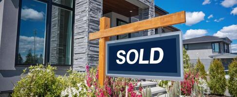 The Sold Sign in Front of a Beautiful Modern Home with Colorful Landscaping photo
