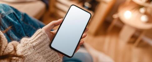 The smartphone in the hand of a cozy individual sitting indoors. photo