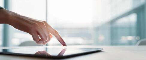 The hand interacting with a tablet in a modern workspace setting. photo