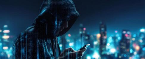 The hooded figure examining data on a mobile device against a city backdrop. photo