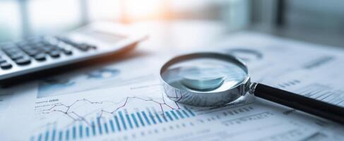 The magnifying glass highlighting financial charts and analysis tools on a desk. photo