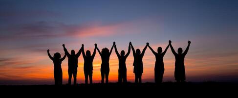 The group of friends celebrating unity against a stunning sunset backdrop. photo