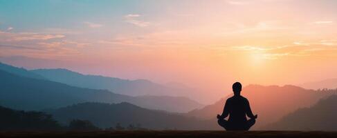 The serene moment of meditation during a vibrant sunset over the mountains. photo