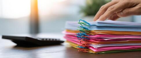 The organized stack of colorful paperwork and office supplies on a desk photo