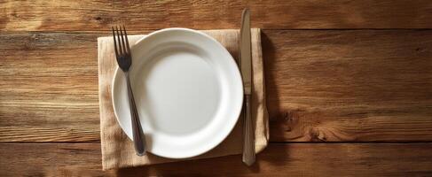 The elegant table setting with a white plate and cutlery on a wooden surface. photo