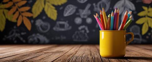 The colorful pencils stand in a yellow cup on a wooden tabletop. photo