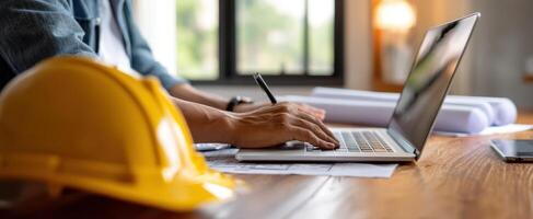 The construction professional working diligently on a laptop with plans. photo