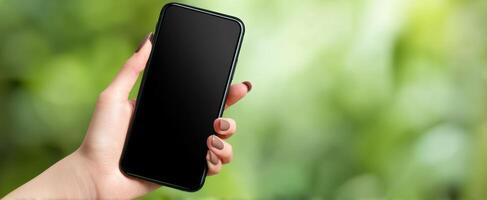 The smartphone held by a hand in a natural green setting photo
