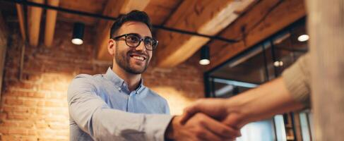 The businessman smiling during a handshake in a modern office setting. photo