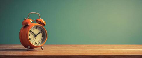 The Orange Alarm Clock on a Wooden Table Against a Green Background photo