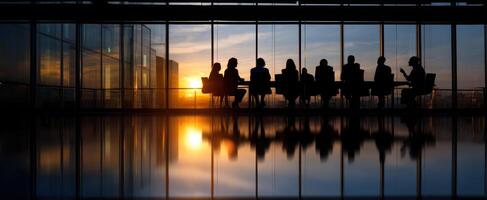 The silhouette of professionals in a meeting against a stunning sunset backdrop. photo
