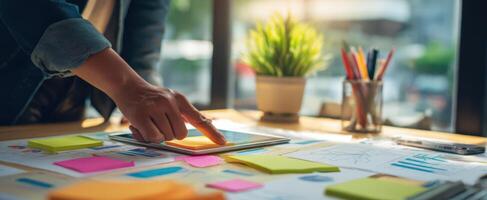 The creative workspace featuring a person interacting with a tablet and colorful notes. photo