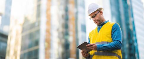 The construction worker using a tablet on a modern urban site. photo