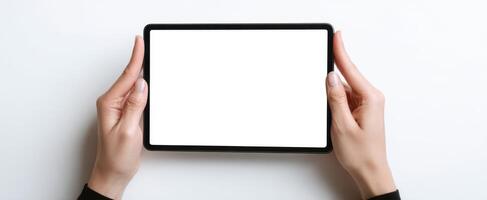The hands holding a tablet with a blank white screen on a clean surface. photo