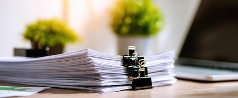 The organized stack of paperwork on a modern office desk with a laptop. photo