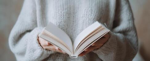 The open book held in cozy hands inspires a moment of quiet reflection. photo