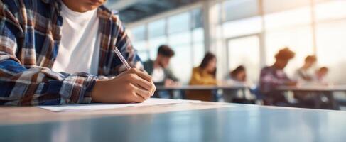 The student focused on writing during a classroom exam session. photo