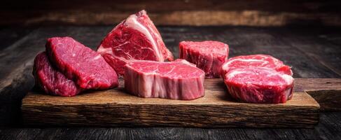 The assortment of premium beef cuts presented on a rustic wooden board. photo