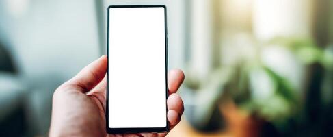 The smartphone held with a blank screen in a cozy indoor setting. photo