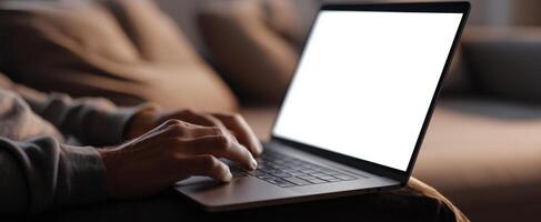 The laptop resting on a cozy couch with hands typing on the keyboard. photo