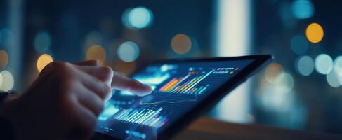 The tablet displaying financial data in a modern urban setting at night. photo