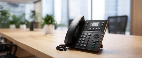 The modern office telephone on a sleek wooden desk in a bright workspace. photo