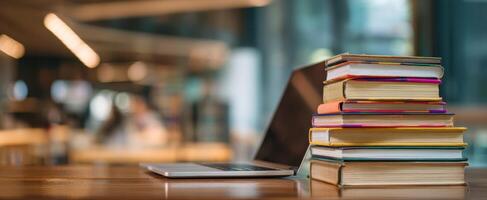 The laptop and colorful books stacked on a wooden desk in a cafe. photo
